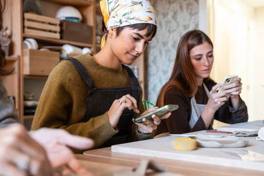 Potters using smartphone during pottery workshop class