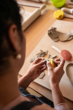 Hands shaping clay piece during pottery workshop at table