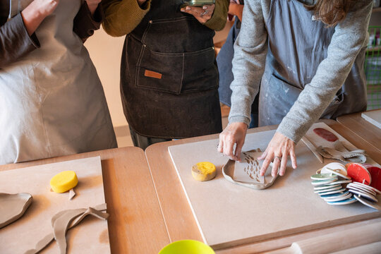 Pottery workshop scene with hands shaping clay on table