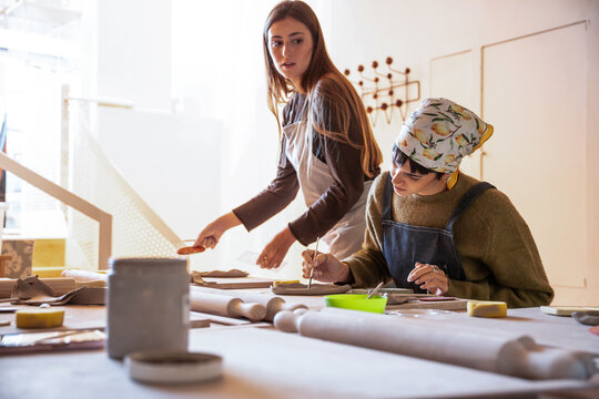 Pottery workshop scene with two women shaping clay together