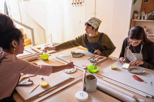Potters painting ceramic pieces during a workshop class