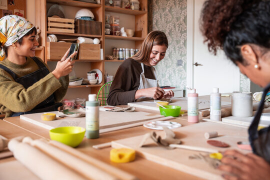 Pottery workshop class with women painting clay pieces together