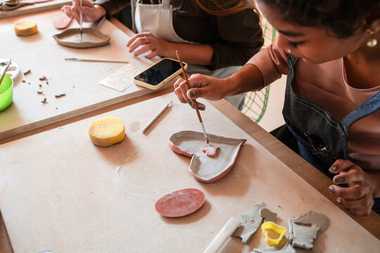 Hands painting clay dish during pottery workshop at table