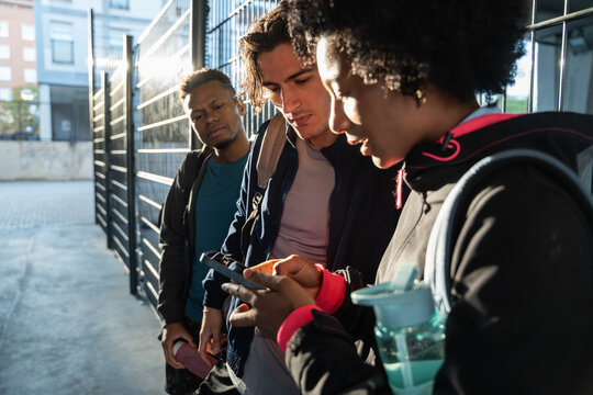 Young friends checking smartphone outside urban building