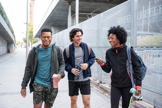 Friends walking outdoors near campus with backpacks and drinks