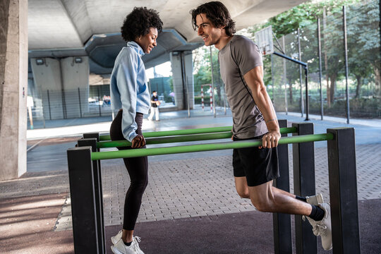 Friends doing outdoor calisthenics dips at park gym