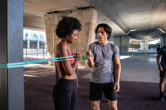 Personal trainer coaching woman with resistance band workout