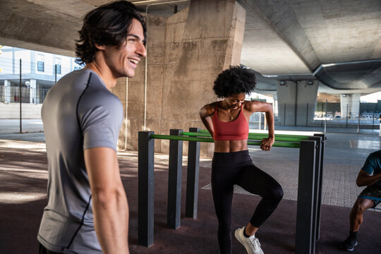 Outdoor workout partners training with dip bar under bridge