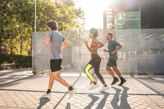 Group jogging together on sunny city court outdoors