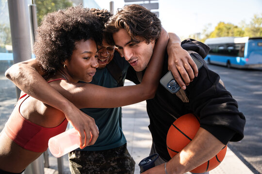 Friends hug on city street after sport with basketball