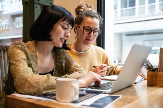 Two women working together on laptop in a cafe office