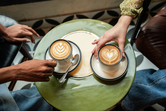 Multiethnic friends sharing latte art coffee at cafe table