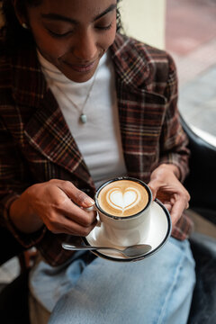 Woman holding latte with heart art in cozy cafe setting