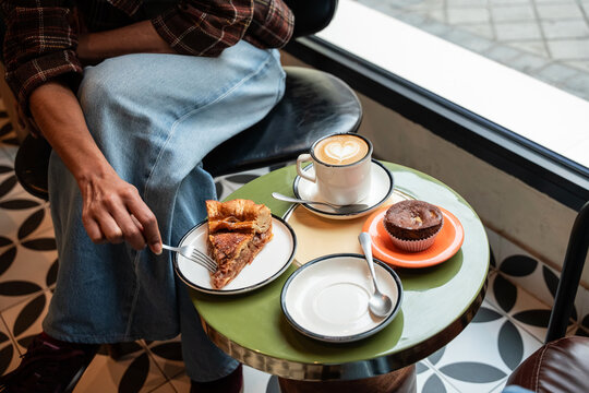 Cozy cafe table with latte art and pastries by window