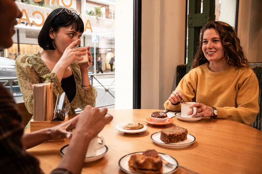 Multiethnic friends having coffee and pastry in cafe