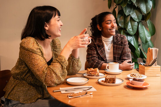 Multiethnic women chatting over coffee and dessert at cafe