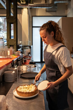 Pastry chef plating a tart in a modern restaurant kitchen