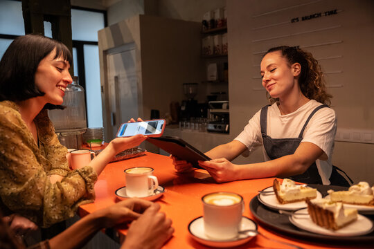 Customer paying by phone at cafe counter with barista