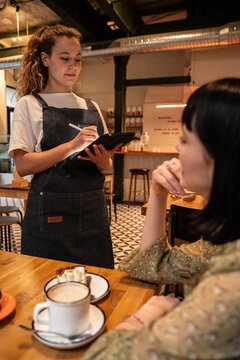 Waitress taking an order on a tablet in modern cafe