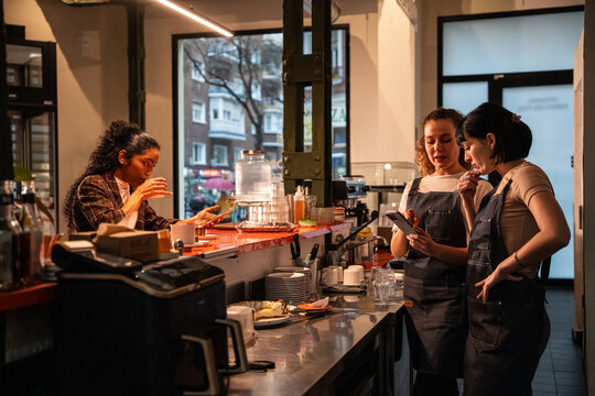 Multiethnic baristas checking phone behind cafe counter