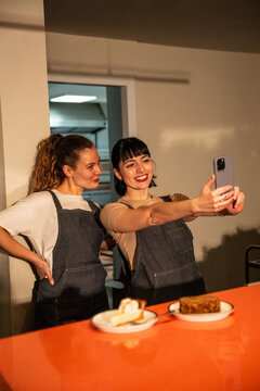 Two baker women taking selfie in warm kitchen after shift