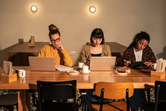 Multiethnic student group studying with laptop in cafe