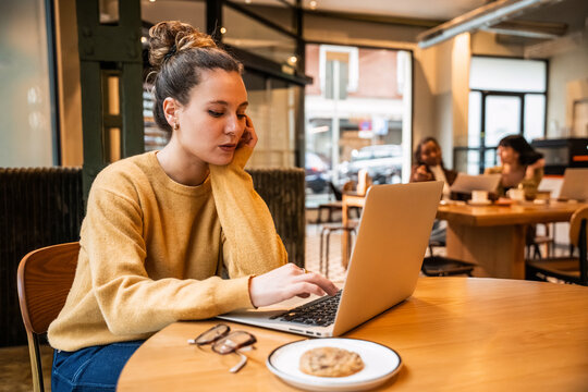 Young woman working on laptop in cozy coffee shop