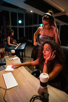 Women producing music in recording studio with keyboard