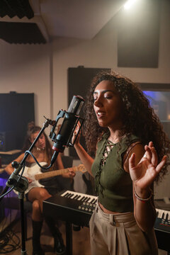 Female singer recording vocal take in music studio session