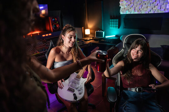 Women relaxing in recording studio with guitar and drink