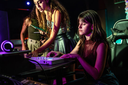 Young woman mixing music on controller in neon club light