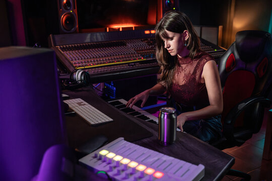 Female musician playing keyboard in modern recording studio