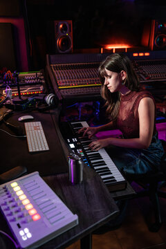 Musician playing MIDI keyboard in modern recording studio