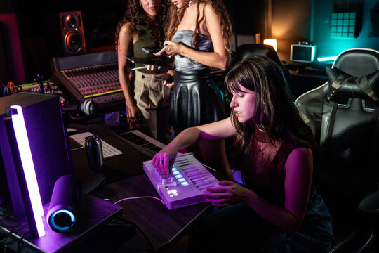 Young woman composing music on MIDI controller in studio
