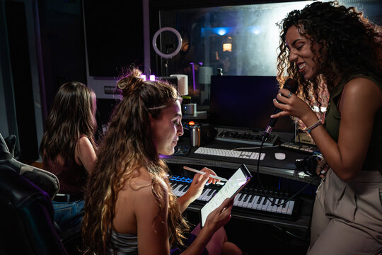 Female vocalist recording in music studio with producer