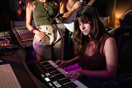 Female musician playing keyboard in professional recording studio