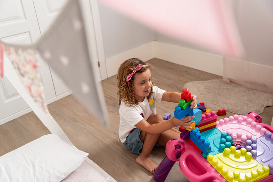 Child playing with colorful building blocks in playroom