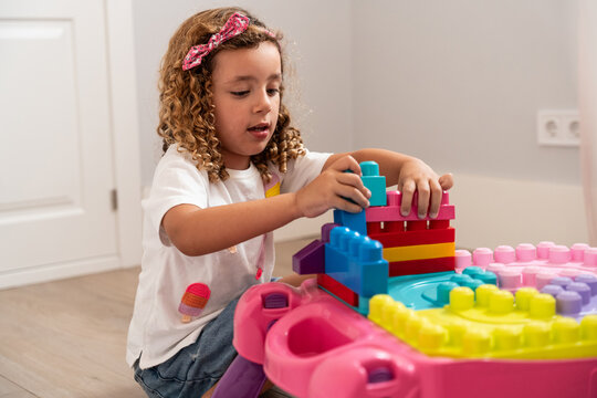 Young girl building colorful blocks at home play table