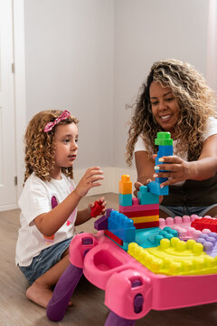 Mother and daughter building colorful block tower at home