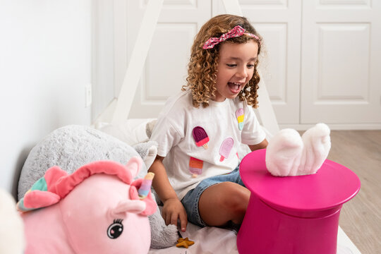 Child playing at home with toy rabbit in magic hat