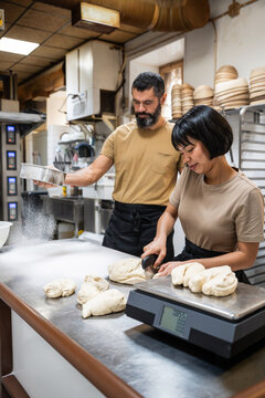 Artisan baker team preparing dough on stainless table