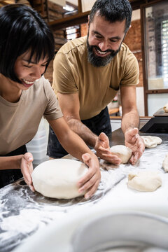 Artisan bakery team shaping dough on floured table