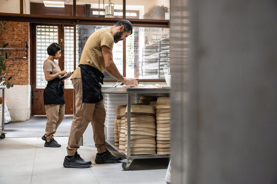 Baker shaping dough at worktable in artisan bakery shop