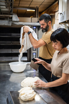 Artisan baker preparing dough in a busy bakery kitchen