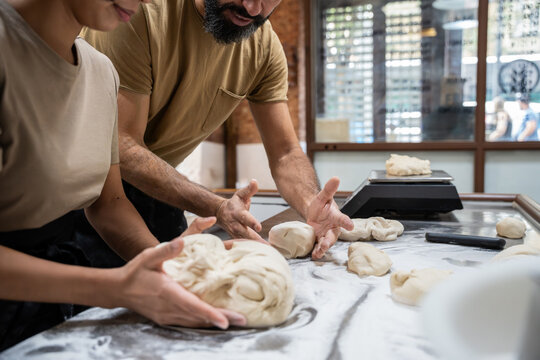 Artisan bakers shaping dough on floured worktable