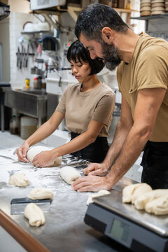 Artisan bakery staff shaping dough on floured table