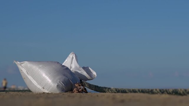 Shoreline fencing made from sandbags tied to a rope and lying on the beach. High quality FullHD footage