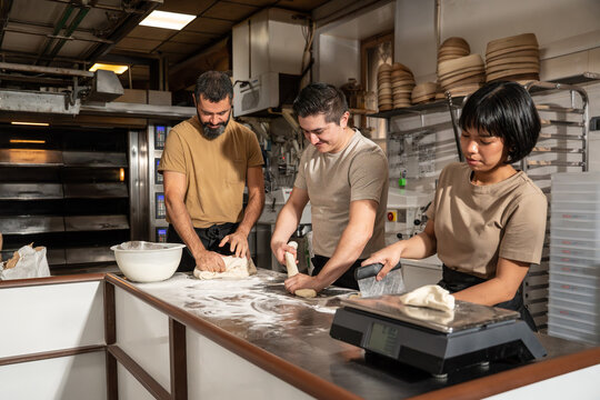 Artisan bakery team shaping dough on a floured bench