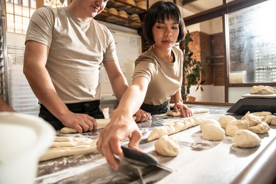 Artisan bakers shaping dough in a busy bakery kitchen