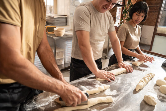 Artisan bakers shaping dough for bread in a warm bakery